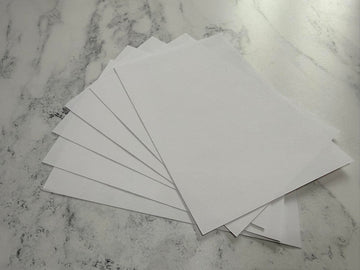 Stack of white envelopes on a marble surface