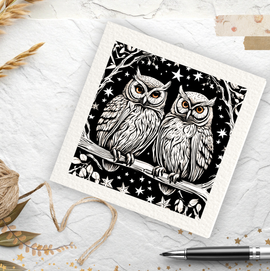 Decorative card with black and white owl design on a textured surface with twine and pen.
