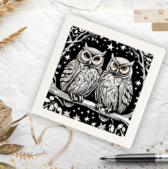 Decorative card with black and white owl design on a textured surface with twine and pen.