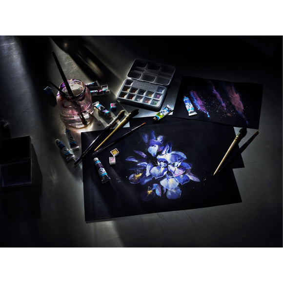 Artistic setup with a painting of flowers on a dark surface, surrounded by art supplies.
